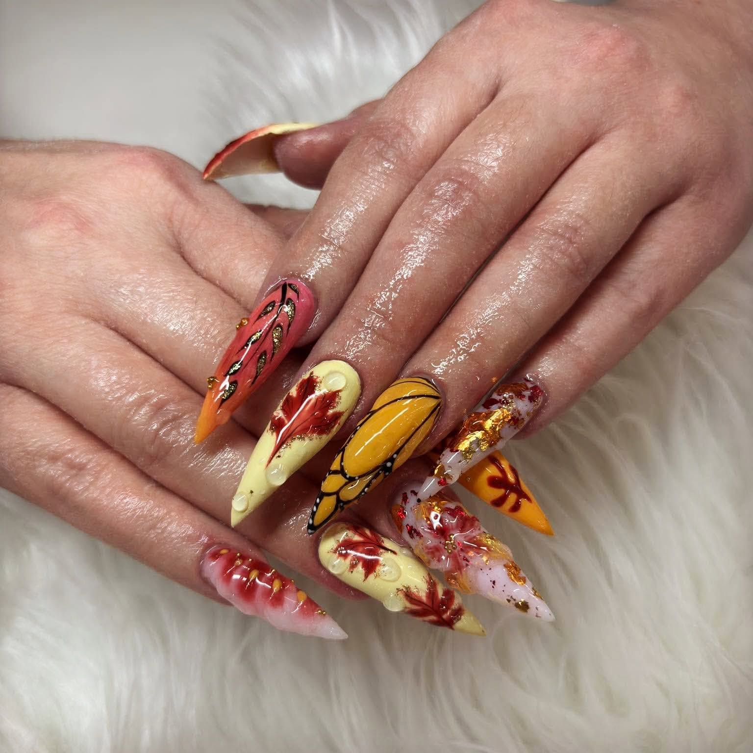 Long pointed acrylic nails with autumn leaf designs, gold foil and raised accents