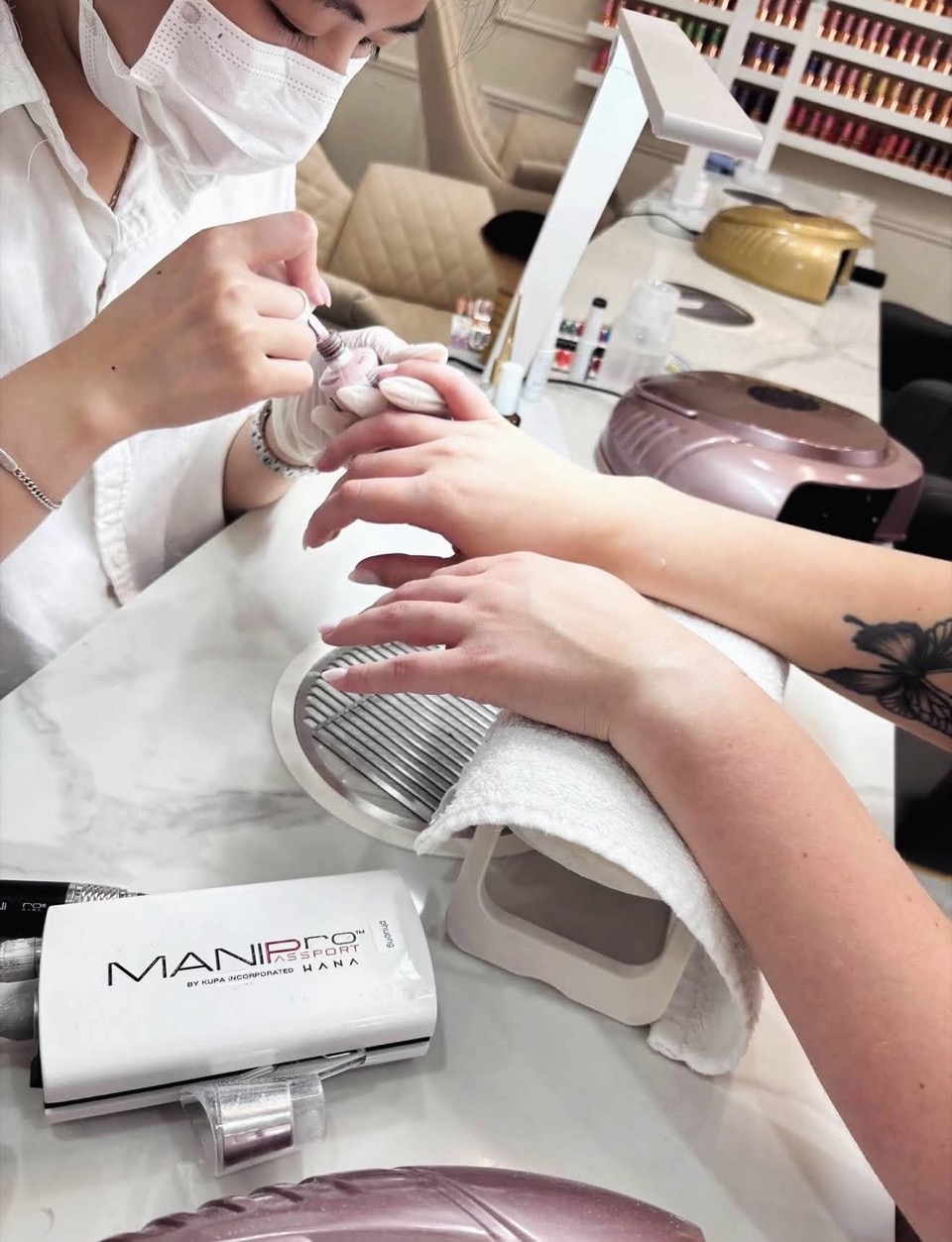 A nail technician shaping a client’s nails at a manicure station.