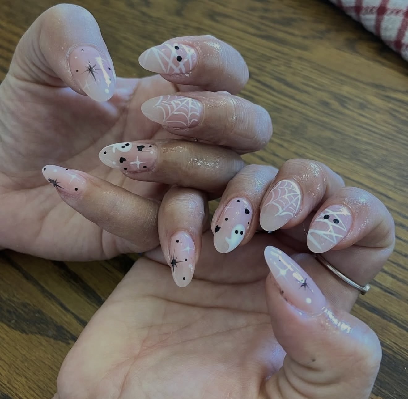 Soft pink almond nails with white ghosts, spiderwebs and black star details